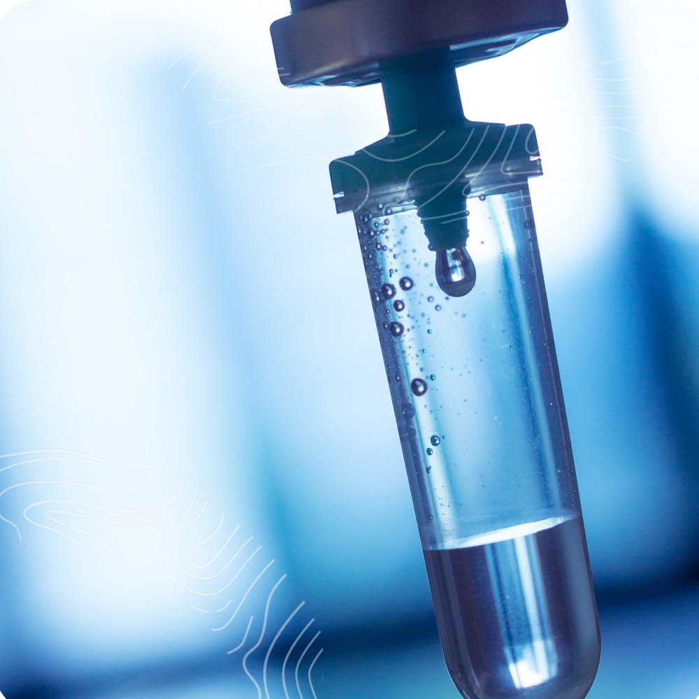 Close-up of a laboratory pipette with a clear liquid inside, set against a blurred blue background.