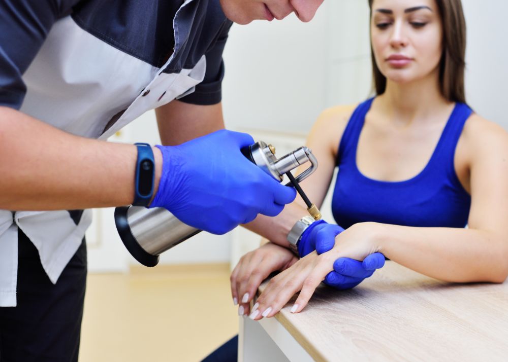 Skin doctor is performing cyrotherapy on another person's hand, checking for signs of skin cancer to ensure optimal skin health.