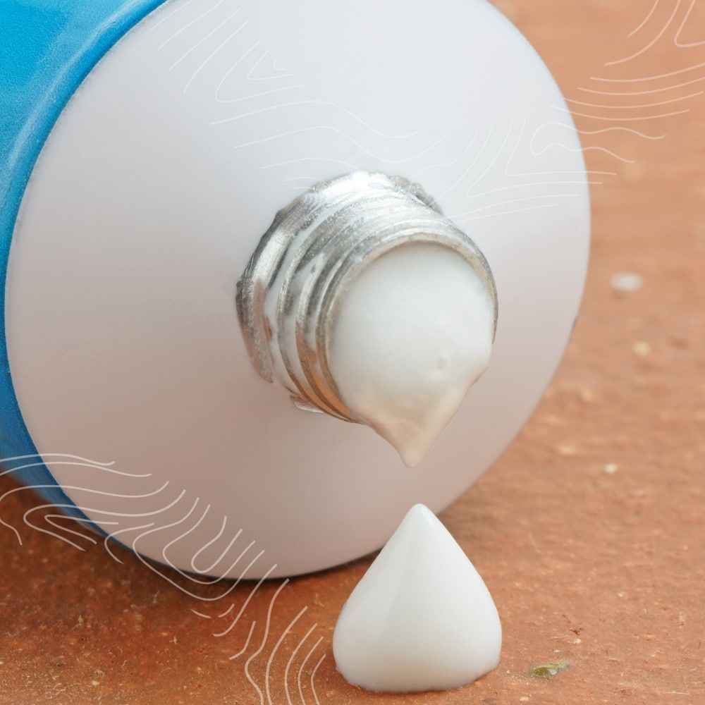 Close-up of a blue tube with white cream oozing out of the nozzle onto a surface, reminiscent of essential skin checks for early detection.