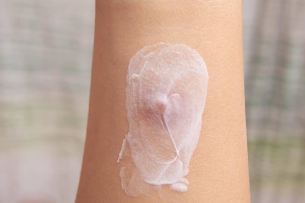 A close-up of a person's arm with a dollop of white lotion or cream spread on the skin, highlighting the importance of skincare to help prevent conditions like squamous cell carcinoma and other non-melanoma skin cancers.